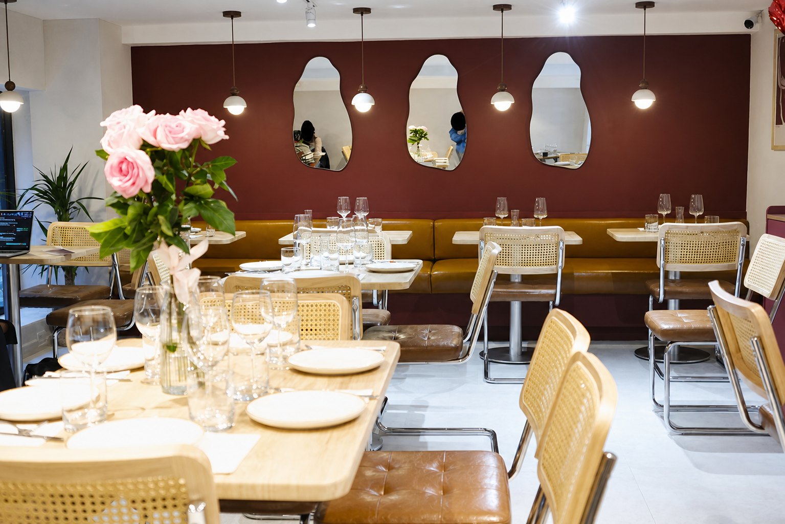 The full dining room — banquette, mirrors, pendant globes