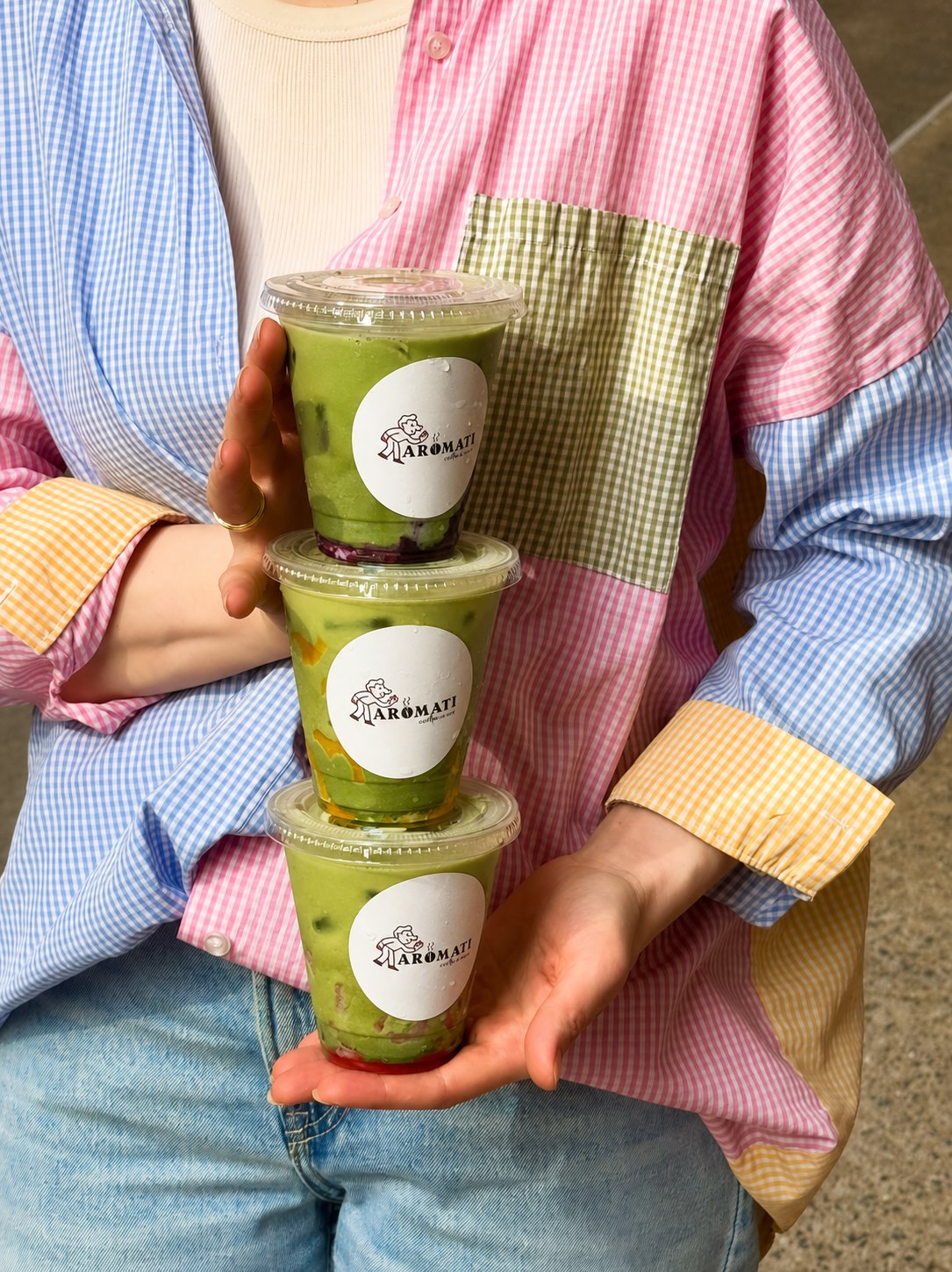 Three fruit matcha lattes held in a stack