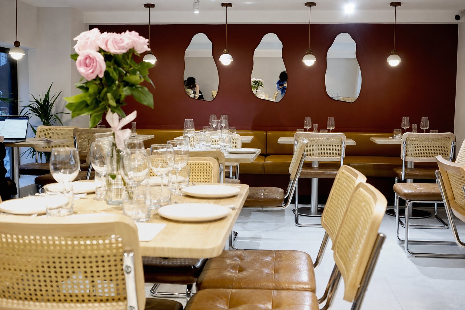 The upstairs dining room at Aromati — cane chairs, tufted leather, burgundy walls